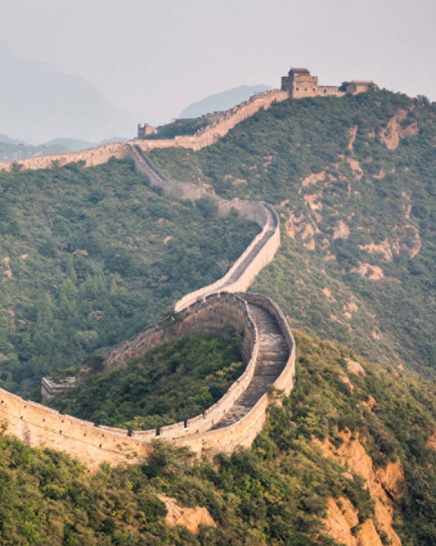 Great Wall of China winding along green mountain