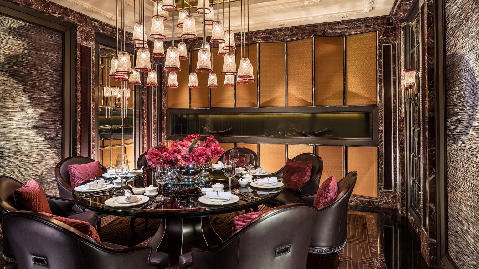 Bell-shaped crystal lights over round dining table with black leather chairs