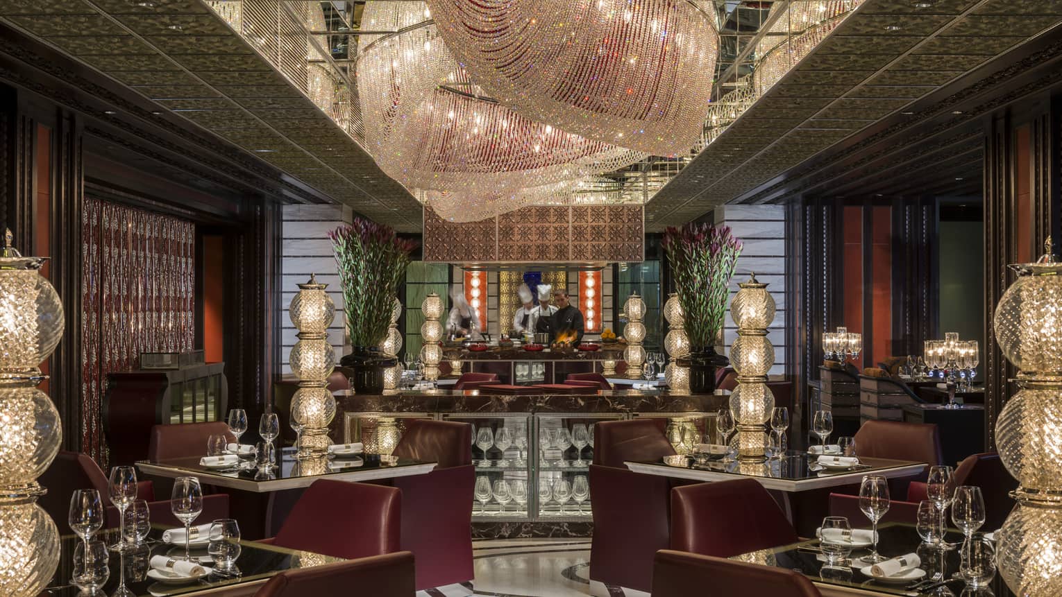 Mio restaurant large, modern crystal chandeliers over dining tables with tall crystal lamps