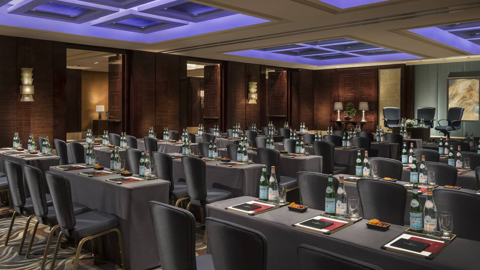Rows of grey meeting tables in modern banquet room under blue accent lights