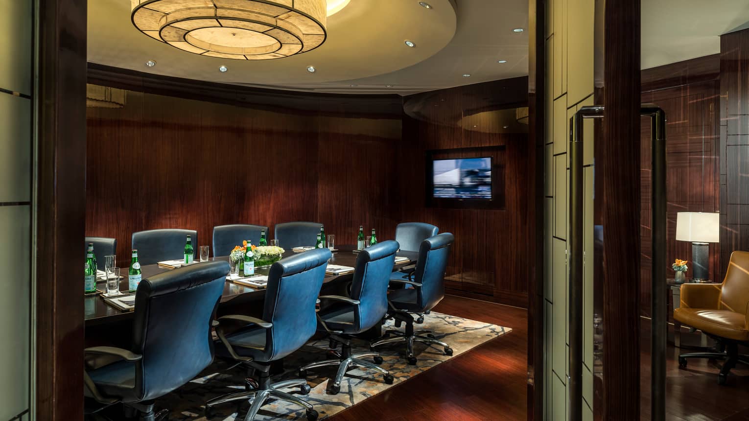 Business Centre meeting table with tall leather chairs, TV screen