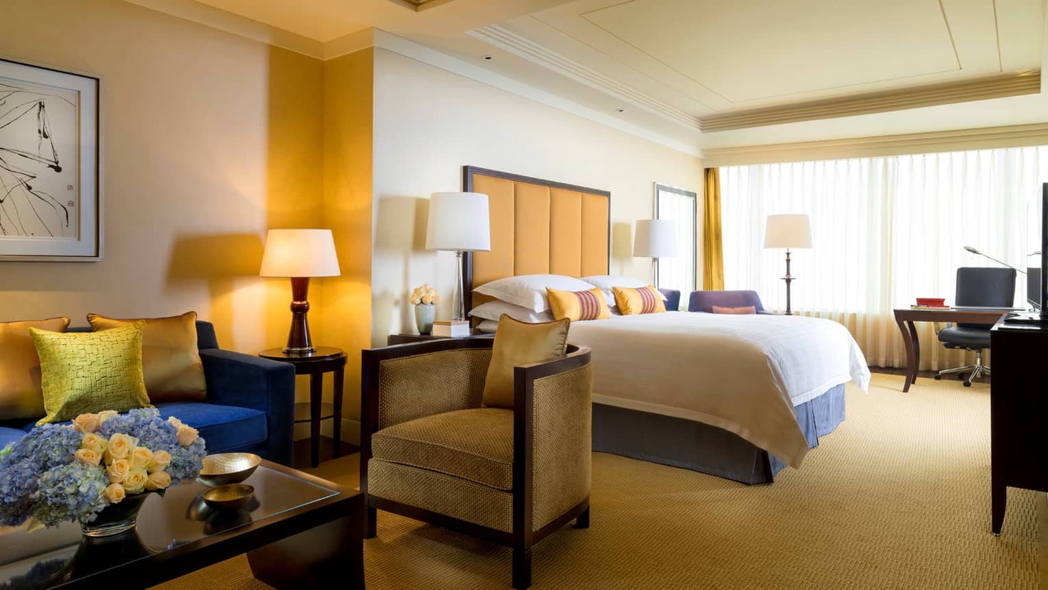Four Seasons Room sitting area with coffee table, small armchairs beside hotel bed