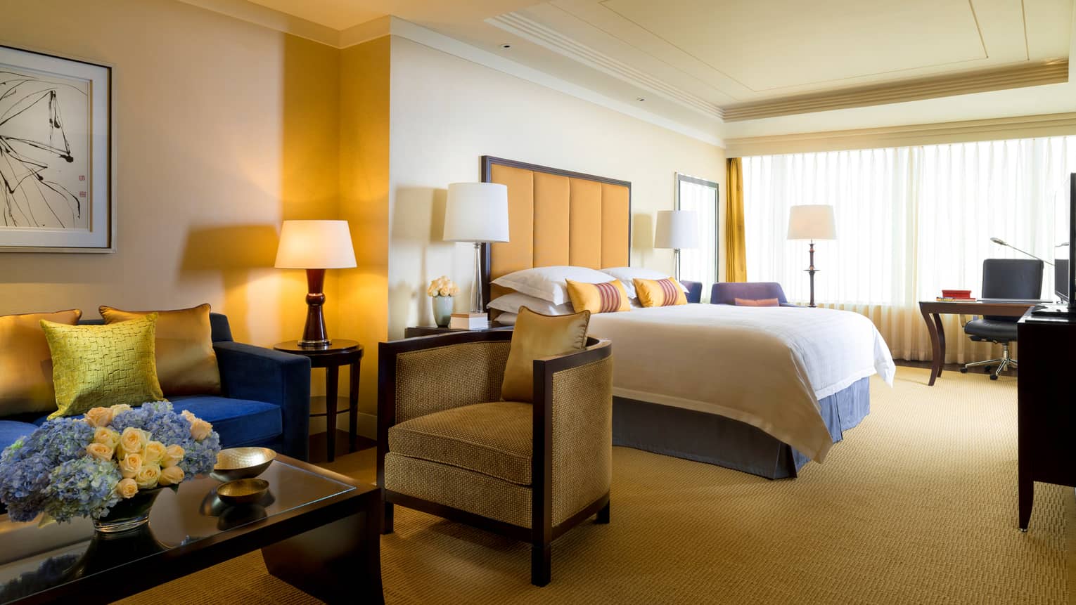 Four Seasons Room sitting area with coffee table, small armchairs beside hotel bed