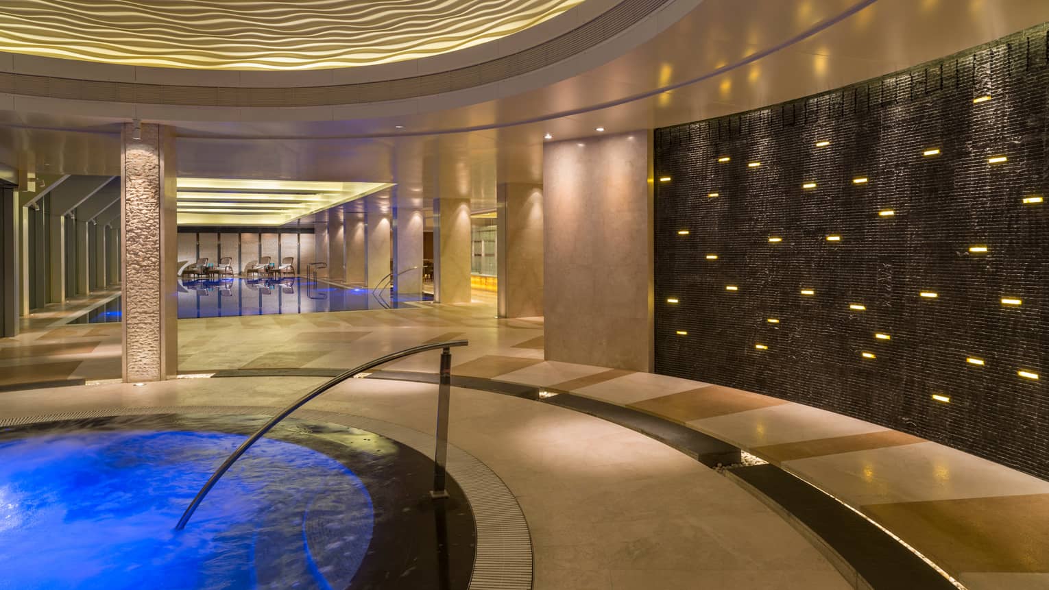 Blue water, stairs of indoor whirlpool, swimming pool in background