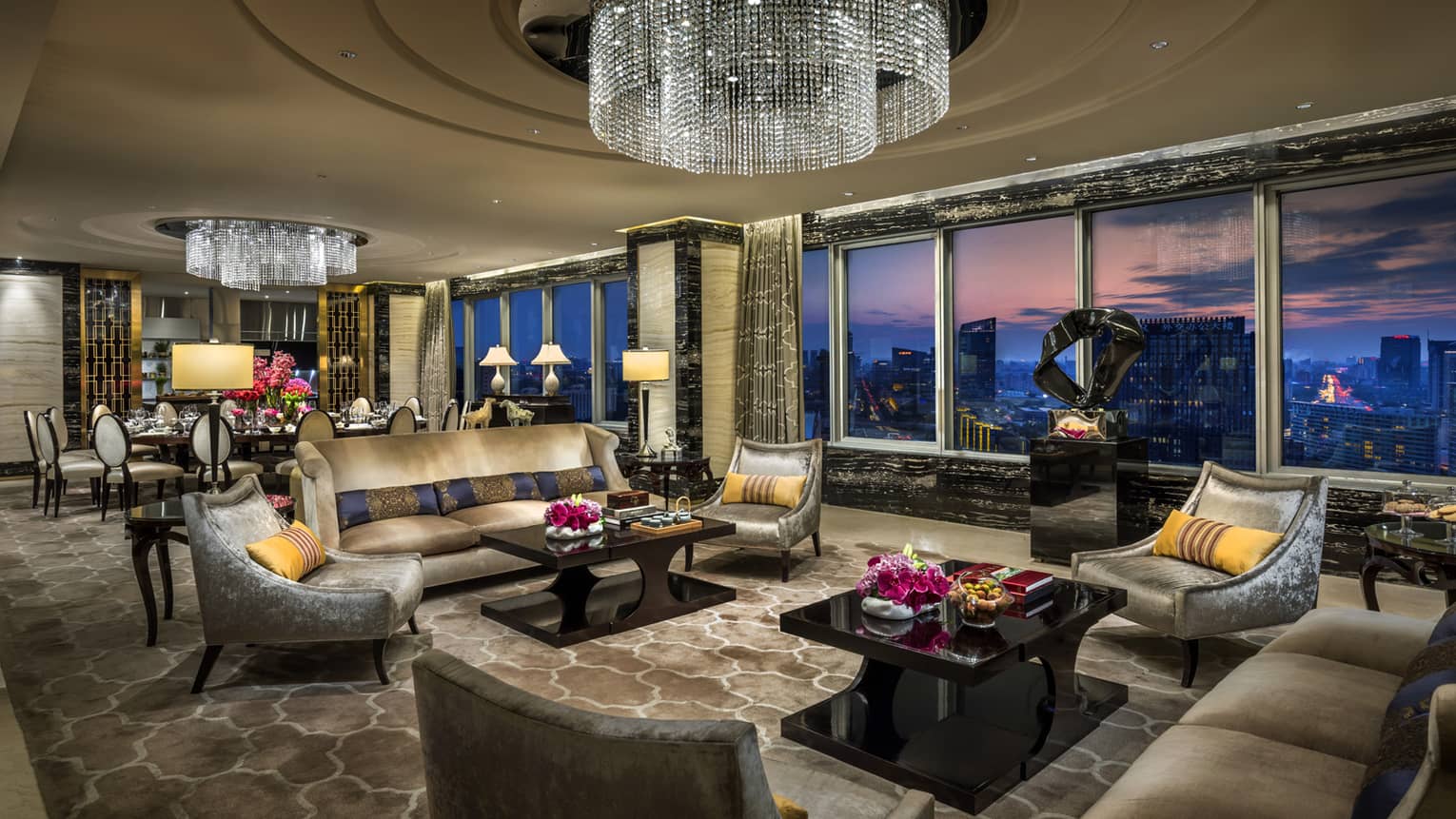 Imperial Suite luxurious living room with sofas, armchairs under large crystal chandeliers, floor-to-ceiling windows, sunset views
