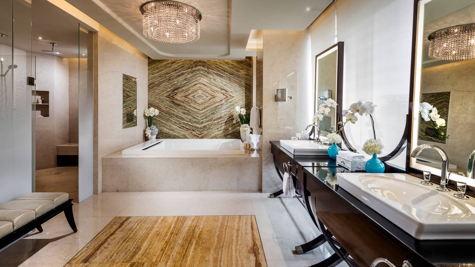 Large bathroom with square marble tub, decorative marble wall, wood vanity with double sinks